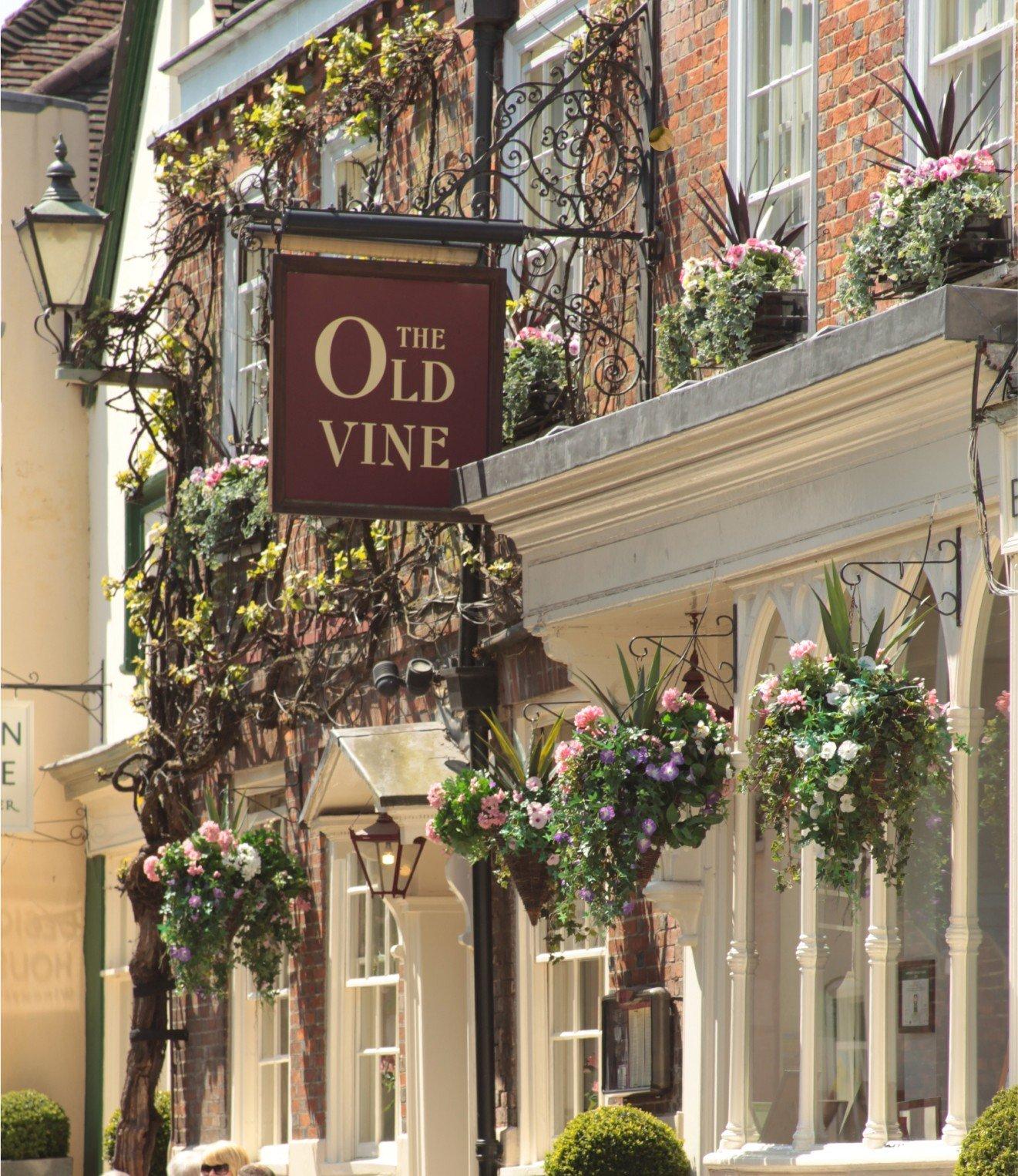 a woman walking down a sidewalk with a sign that says the old wine